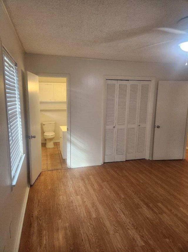 1100 8th St, Cooper, TX 75432 - unfurnished bedroom featuring wood finished floors, a textured ceiling, a closet, and ensuite bath