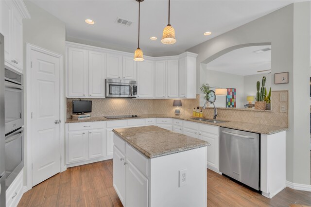 3712 Stockport Dr, Plano, TX 75025 - kitchen with appliances with stainless steel finishes, a sink, a kitchen island, backsplash, and arched walkways