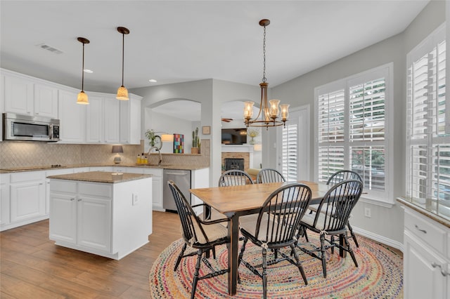 3712 Stockport Dr, Plano, TX 75025 - dining space with wood finished floors, a fireplace, recessed lighting, arched walkways, and a chandelier