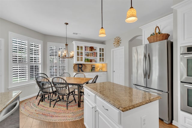 3712 Stockport Dr, Plano, TX 75025 - kitchen featuring stainless steel appliances, a kitchen island, glass insert cabinets, light wood-style flooring, and white cabinets