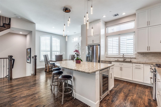 731 Spanish Oaks Pl, Dallas, TX 75204 - kitchen with stainless steel appliances, a sink, beverage cooler, dark wood-style floors, and a center island