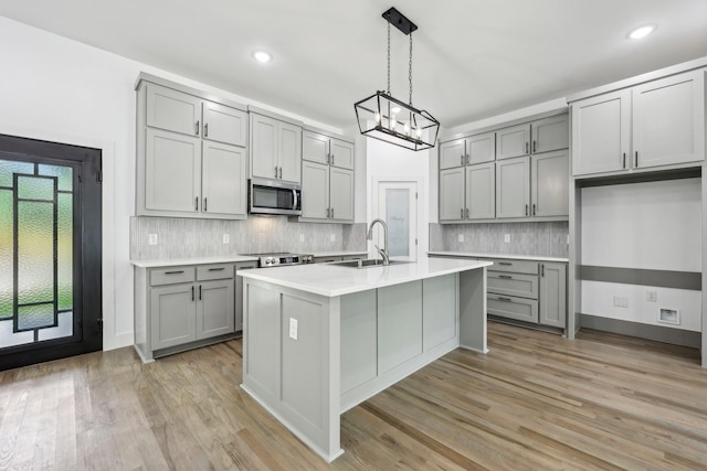 6002 Verde Way, Dallas, TX 75211 - kitchen featuring gray cabinetry, stainless steel microwave, a sink, a chandelier, and light wood finished floors