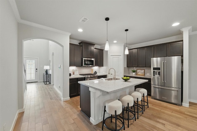 2101 Chebi Ln, Denton, TX 76209 - kitchen with premium appliances, arched walkways, dark brown cabinets, crown molding, and light wood finished floors