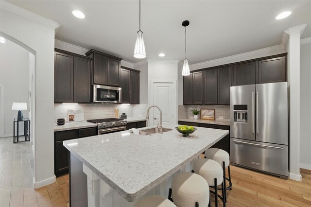 2101 Chebi Ln, Denton, TX 76209 - kitchen with high quality appliances, a breakfast bar area, dark brown cabinetry, crown molding, and light wood-style floors