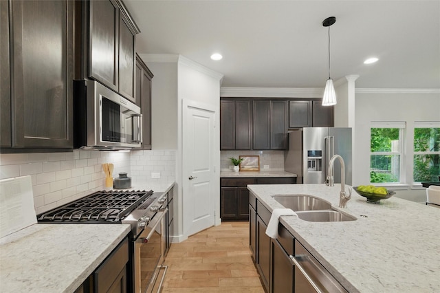 2101 Chebi Ln, Denton, TX 76209 - kitchen featuring appliances with stainless steel finishes, crown molding, light wood-type flooring, dark brown cabinets, and hanging light fixtures