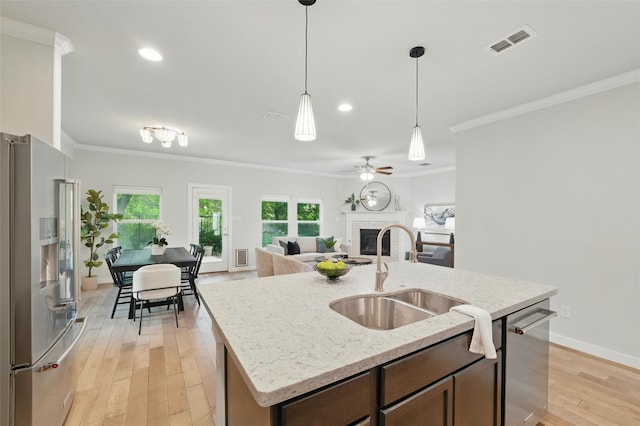 2101 Chebi Ln, Denton, TX 76209 - kitchen with appliances with stainless steel finishes, a brick fireplace, crown molding, light wood-type flooring, and decorative light fixtures