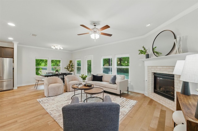 2101 Chebi Ln, Denton, TX 76209 - living room with crown molding, a ceiling fan, light wood-type flooring, a brick fireplace, and recessed lighting