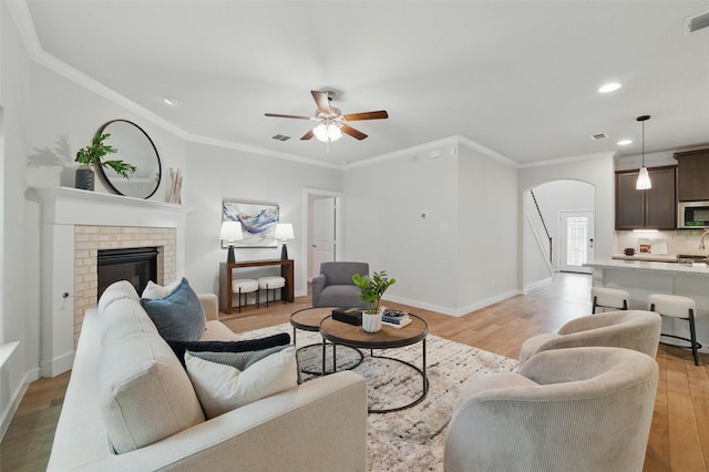2101 Chebi Ln, Denton, TX 76209 - living area featuring arched walkways, a ceiling fan, light wood-style floors, a brick fireplace, and recessed lighting