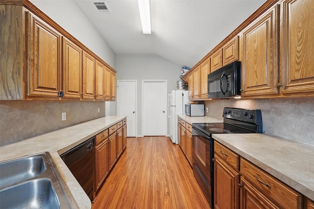 10700 Irish Glen Trl, Haslet, TX 76052 - kitchen featuring black appliances, vaulted ceiling, light wood finished floors, light countertops, and brown cabinets