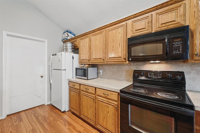 10700 Irish Glen Trl, Haslet, TX 76052 - kitchen with black appliances, vaulted ceiling, decorative backsplash, light countertops, and light wood-type flooring