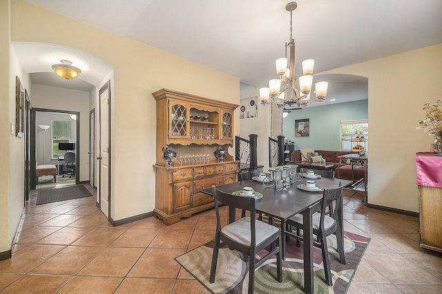 5716 Wall Ave, Haltom City, TX 76117 - dining space with arched walkways, a chandelier, light tile patterned floors, and baseboards