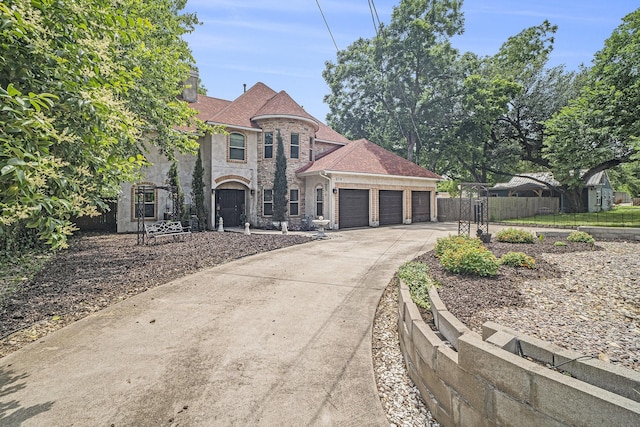 5716 Wall Ave, Haltom City, TX 76117 - french country style house featuring an attached garage, concrete driveway, stone siding, and a gate