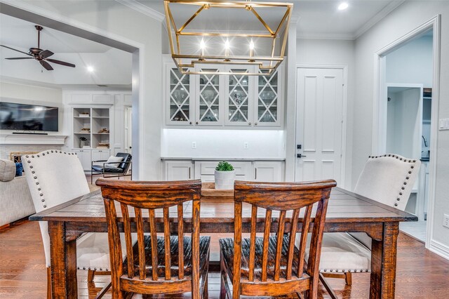 5932 Royal Palm Dr, Plano, TX 75093 - dining area featuring dark wood-style flooring, a ceiling fan, crown molding, a bar, and a fireplace