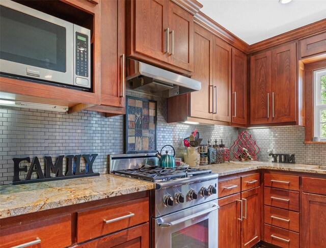 3614 Birdwell Dr, Tyler, TX 75701 - kitchen featuring stainless steel appliances, under cabinet range hood, backsplash, brown cabinets, and light stone countertops