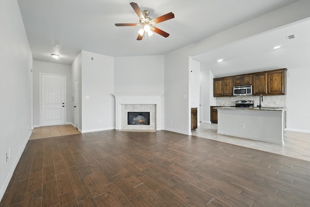 237 Cedar Crest Dr, Justin, TX 76247 - unfurnished living room featuring wood finished floors, ceiling fan, a tiled fireplace, and baseboards