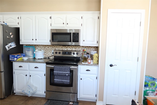 2003 Hearthside Ln, Garland, TX 75044 - kitchen with stainless steel appliances, white cabinetry, tasteful backsplash, and dark tile patterned flooring
