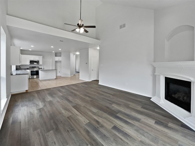 3032 Thicket Bend Ct, Fort Worth, TX 76244 - unfurnished living room with a ceiling fan, wood finished floors, high vaulted ceiling, a glass covered fireplace, and recessed lighting