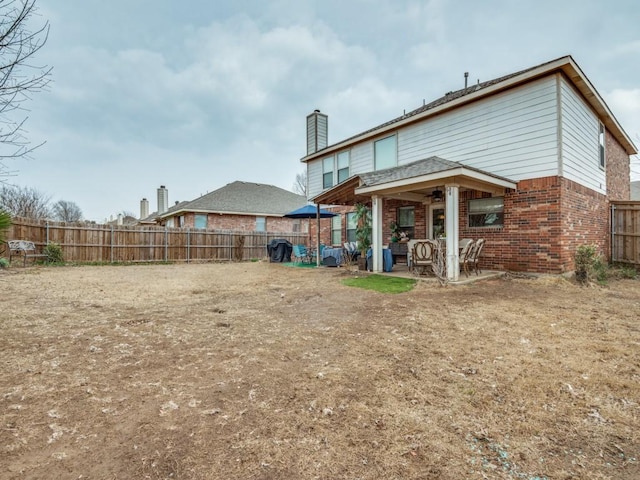 2852 Ector Dr, Grand Prairie, TX 75052 - back of house featuring brick siding, a fenced backyard, a patio area, and a chimney