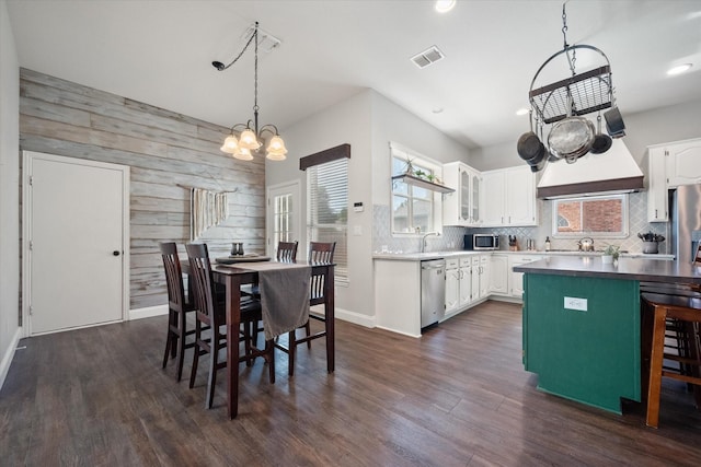 1817 Meadow Ridge Dr, Flower Mound, TX 75028 - kitchen with plenty of natural light, appliances with stainless steel finishes, white cabinetry, wooden walls, and a chandelier