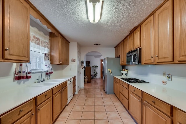 5310 Ranchero Ln, Dallas, TX 75236 - kitchen featuring appliances with stainless steel finishes, arched walkways, a textured ceiling, a sink, and light countertops