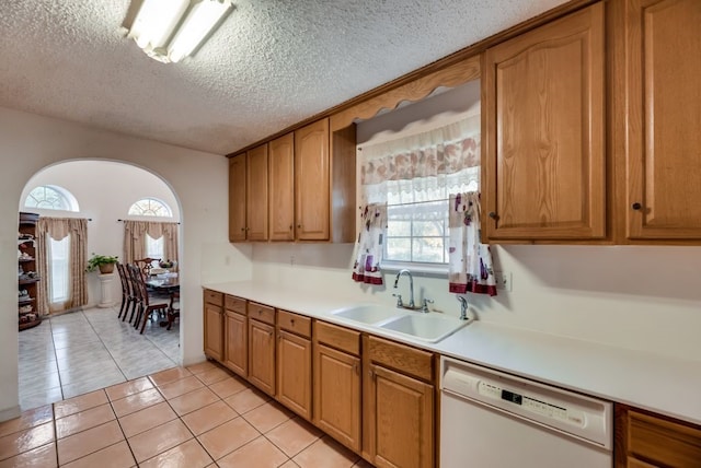 5310 Ranchero Ln, Dallas, TX 75236 - kitchen with white dishwasher, a sink, light tile patterned floors, light countertops, and brown cabinetry