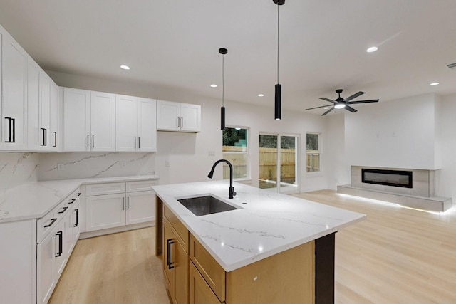 4519 Wahoo St, Dallas, TX 75210 - kitchen with a sink, light wood finished floors, a ceiling fan, a glass covered fireplace, and light stone counters
