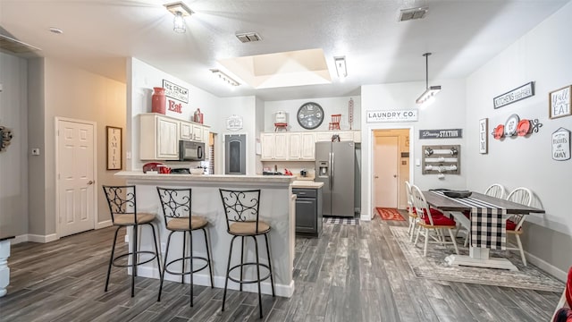 1228 Meadow Gln, Crowley, TX 76036 - kitchen with stainless steel fridge, black microwave, a breakfast bar area, dark wood-style floors, and a peninsula