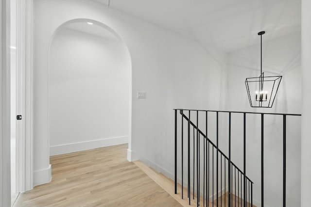 6607 Kenwell St, Dallas, TX 75209 - hallway with arched walkways, an upstairs landing, a chandelier, wood finished floors, and baseboards