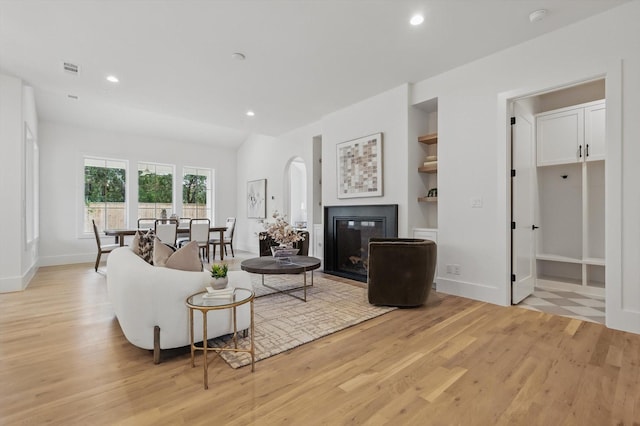6607 Kenwell St, Dallas, TX 75209 - living area with light wood-style flooring, a glass covered fireplace, recessed lighting, arched walkways, and baseboards