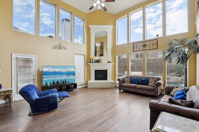 5400 Ivyridge Ln, Mckinney, TX 75071 - living room featuring a ceiling fan, a high ceiling, wood finished floors, and a fireplace with raised hearth