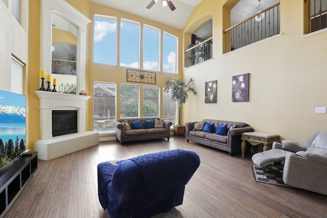 5400 Ivyridge Ln, Mckinney, TX 75071 - living area featuring a ceiling fan, a towering ceiling, hardwood / wood-style floors, and a glass covered fireplace