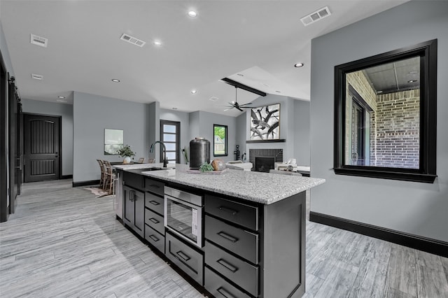 58 Lone Oak Blvd, Pottsboro, TX 75076 - kitchen with stainless steel microwave, a fireplace, baseboards, light wood-type flooring, and recessed lighting