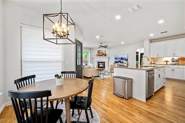 7812 Rockledge Dr, Mckinney, TX 75071 - dining room with a glass covered fireplace, light wood-style floors, a ceiling fan, recessed lighting, and a chandelier