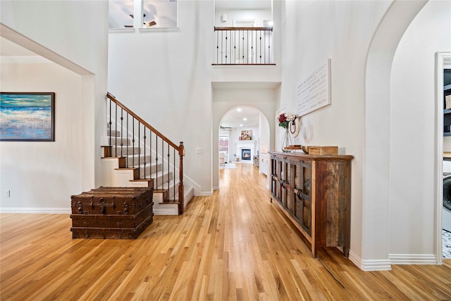 7812 Rockledge Dr, Mckinney, TX 75071 - entrance foyer with arched walkways, wood finished floors, a high ceiling, baseboards, and a glass covered fireplace