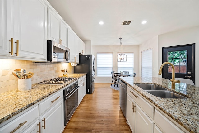7812 Rockledge Dr, Mckinney, TX 75071 - kitchen with stainless steel appliances, a sink, white cabinets, light wood finished floors, and decorative backsplash