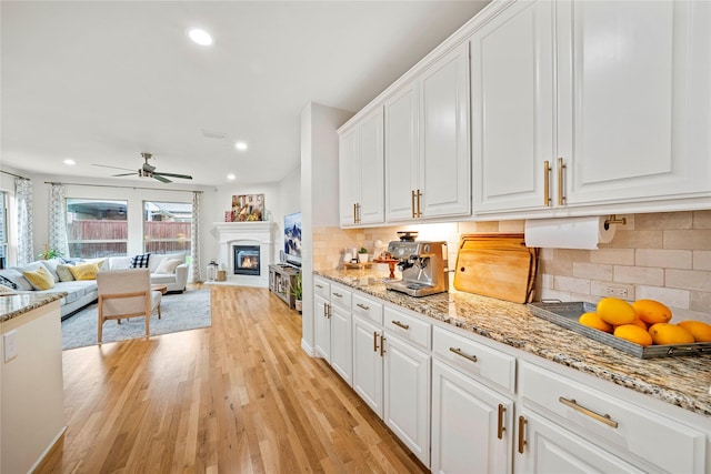 7812 Rockledge Dr, Mckinney, TX 75071 - kitchen featuring white cabinets, light wood-style flooring, a glass covered fireplace, tasteful backsplash, and recessed lighting