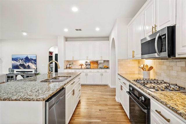 7812 Rockledge Dr, Mckinney, TX 75071 - kitchen featuring appliances with stainless steel finishes, arched walkways, a sink, light wood-style floors, and recessed lighting