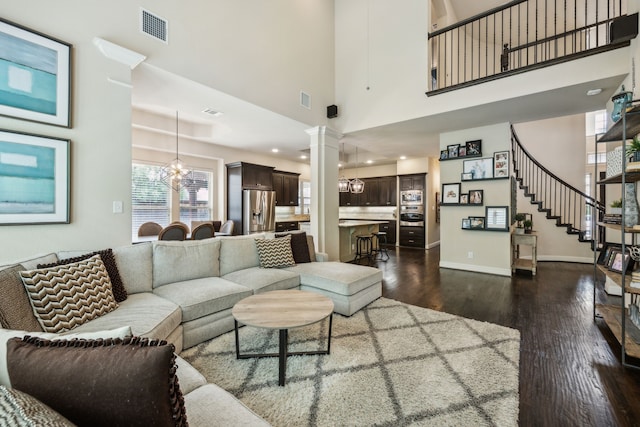 18261 Brighton Grn, Dallas, TX 75252 - living room featuring dark wood-style flooring, a chandelier, a high ceiling, baseboards, and ornate columns