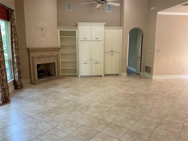 5704 El Campo Ave, Fort Worth, TX 76107 - unfurnished living room with a ceiling fan, a towering ceiling, arched walkways, a fireplace with raised hearth, and baseboards