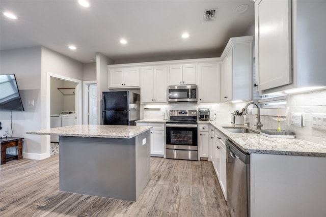 205 W Travis St, Howe, TX 75459 - kitchen featuring appliances with stainless steel finishes, a sink, separate washer and dryer, a center island, and tasteful backsplash