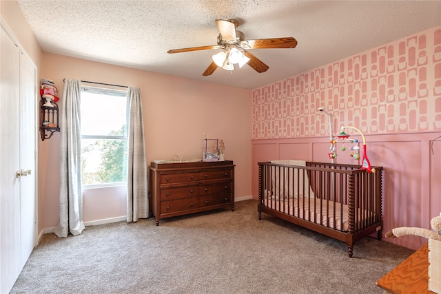 2036 Shawnee Trl, Fort Worth, TX 76247 - carpeted bedroom with a nursery area, a ceiling fan, a textured ceiling, and wainscoting