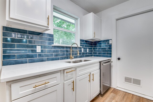 626 Thrush Ave, Duncanville, TX 75116 - kitchen featuring a sink, dishwasher, white cabinets, light wood-style floors, and decorative backsplash