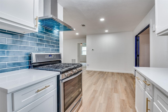 626 Thrush Ave, Duncanville, TX 75116 - kitchen featuring stainless steel range with gas cooktop, wall chimney range hood, light wood-style flooring, backsplash, and white cabinetry