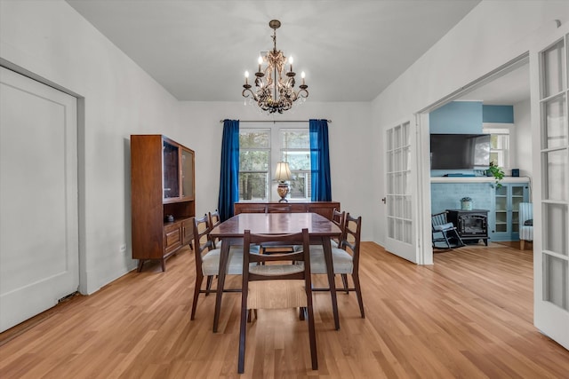 1710 Mckenzie Ave, Waco, TX 76708 - dining area featuring light wood-style floors, a chandelier, a wood stove, and baseboards