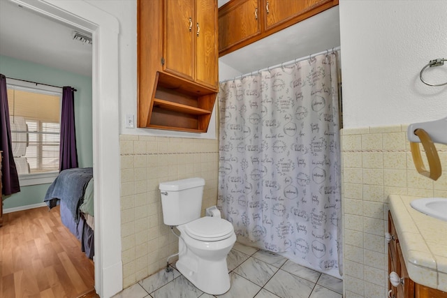 1710 Mckenzie Ave, Waco, TX 76708 - full bathroom featuring tile walls, toilet, vanity, a shower with curtain, and wainscoting
