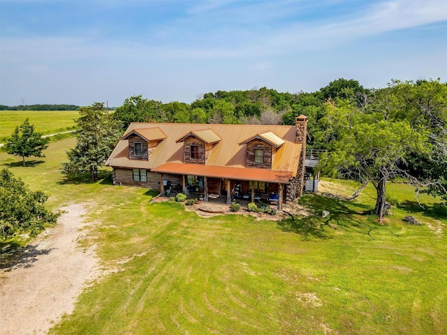 view of front of home with dirt driveway, a chimney, a front yard, and log siding