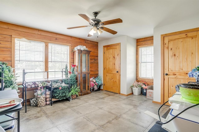 entrance foyer featuring wood walls and a ceiling fan