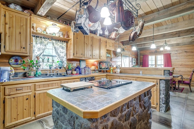 kitchen with a sink, a peninsula, wood ceiling with exposed beams, tile counters, and a center island