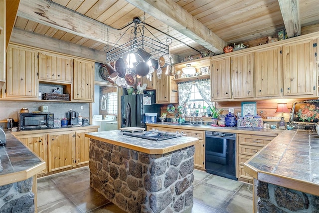 kitchen featuring tile countertops, black appliances, independent washer and dryer, a sink, and wooden ceiling with exposed beams