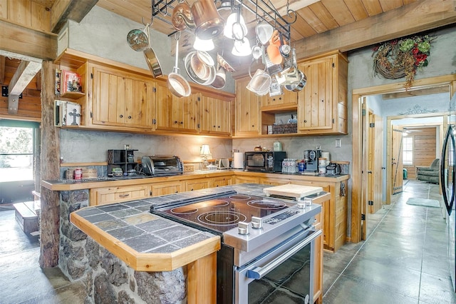 kitchen featuring range with two ovens, open shelves, tile counters, and wooden ceiling with exposed beams
